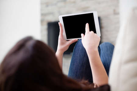 Woman using digital tablet on couchの写真素材
