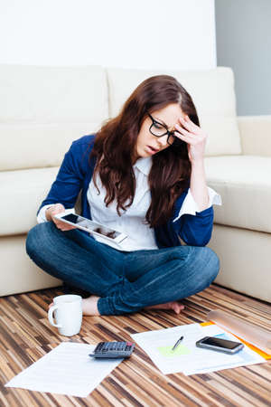 Worried woman paying bills at homeの写真素材