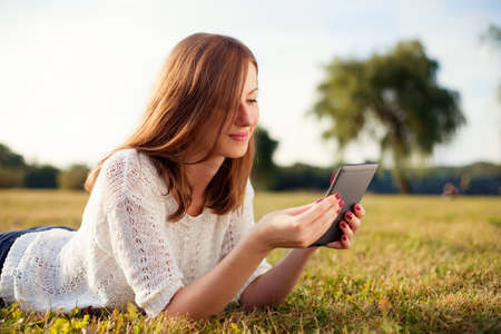 Beautiful young woman with digital tablet in park