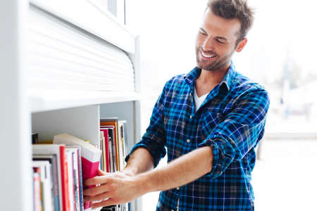Student choosing book in library from bookstandの写真素材