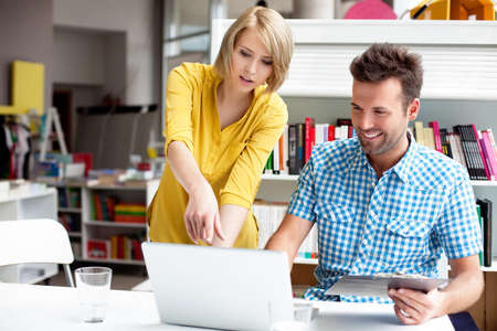 Two bookshop managers working on laptop.