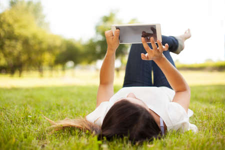 Woman using tablet outdoor laying on grass