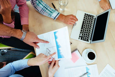 Group of business people discussing graphs sitting at the table.