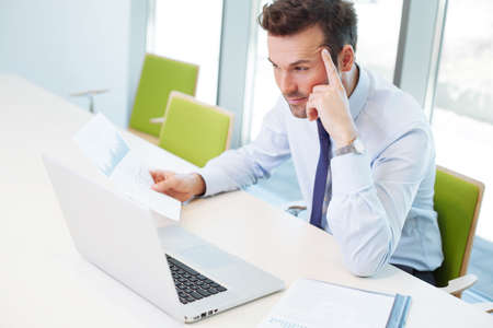 Thoughtful businessman working on laptop