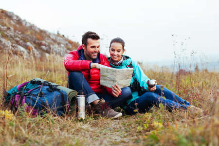 Couple of tourist reading map, sitting on the ground.の写真素材