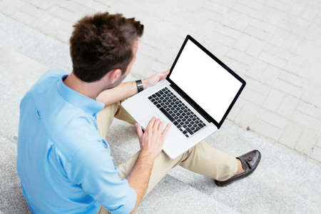 Businessman working on his laptop outside a building
