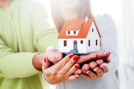 Man and a woman holding a minature houseの写真素材