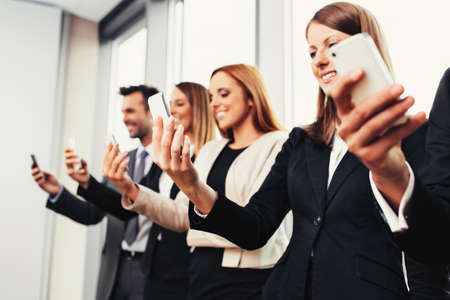 Group of business people standing with smartphonesの写真素材