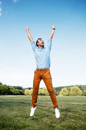 Photo of a joyful man jumping victoriouslyの写真素材