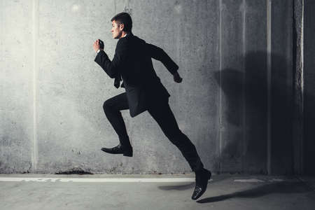 Photo of a young professional running against a concrete backgroundの写真素材