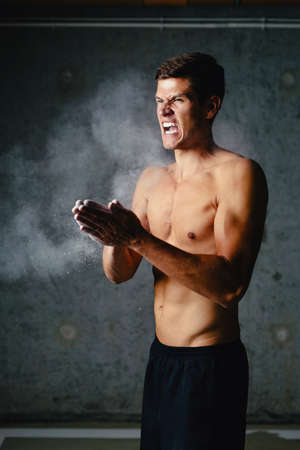 Determined athlete putting talc on his hands and getting readyの写真素材