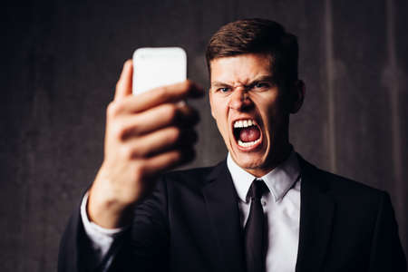 Angry businessman yelling after having read an smsの写真素材