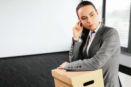 Photo of an attractive woman with a carton on her lap after being made redundantの写真素材