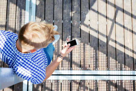 Bird's eye photo of a blonde man texting on his mobile