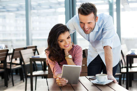 Couple of young smiling people looking at a digital tabletの写真素材