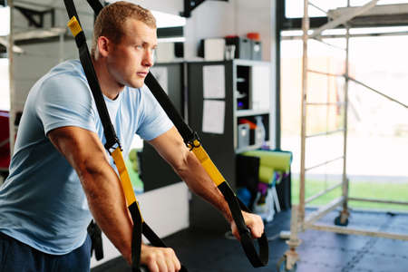 Photo of a muscular man doing a suspension training