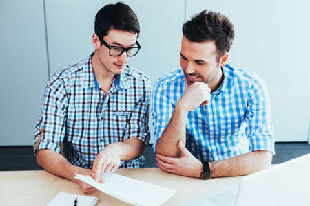 Two webdesigners  discussing their ideas with a pen and paperの写真素材