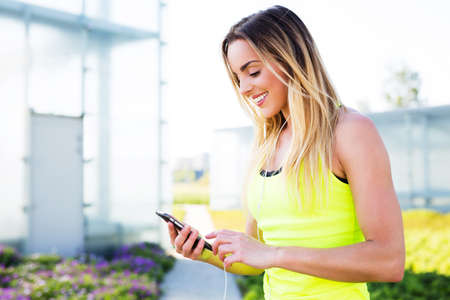 Young pretty female runner using smartphoneの写真素材