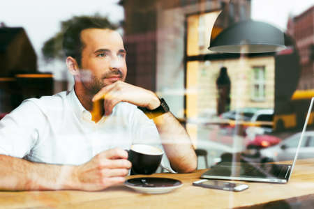 thoughtful man looking through window at cafeteria.の写真素材