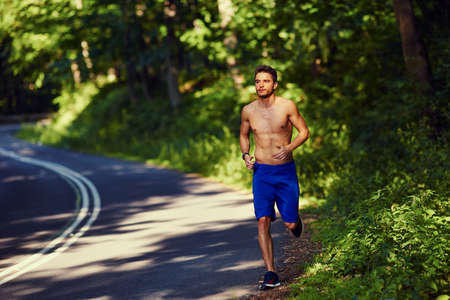 Young man running on road in mountainsの写真素材