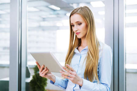 Businesswoman standing in an office and holding a digital tabletの写真素材