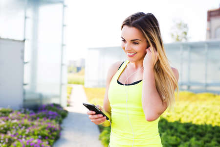 Young female runner plug in earphone before workout