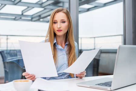 Young business woman comparing documents at officeの写真素材