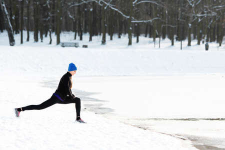 Young woman stretches during winter runの写真素材