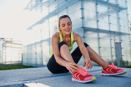 Happy female runner tying shoelaces