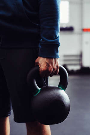 Closeup of man holding kettlebell at gymの写真素材