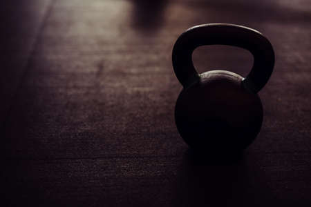 silhouette of heavy kettlebell on black floorの写真素材
