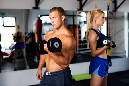 Young couple training at gym with dumbbells