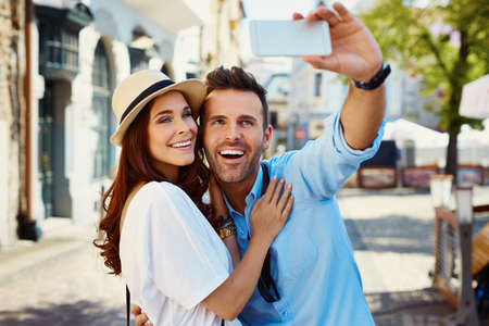 Happy couple taking selfie on the city streetの写真素材