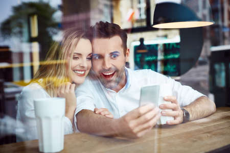 Couple taking selfie in coffee shopの写真素材