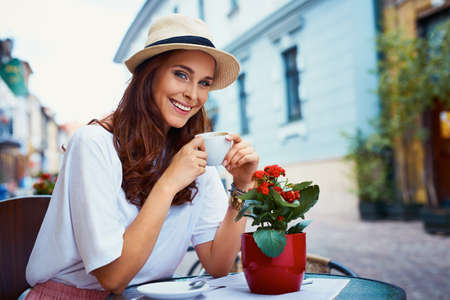 Attractive woman drinking coffee in outdoor cafeの写真素材