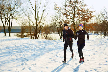 Caucasian couple running at winterの写真素材