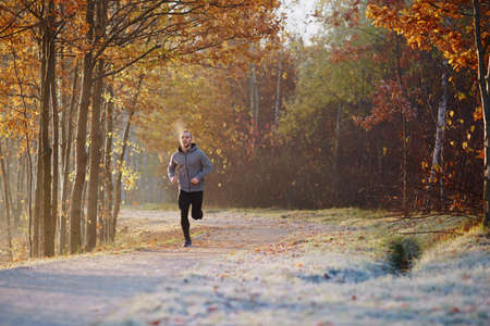 Young man running in the park during cold autumn morningの写真素材