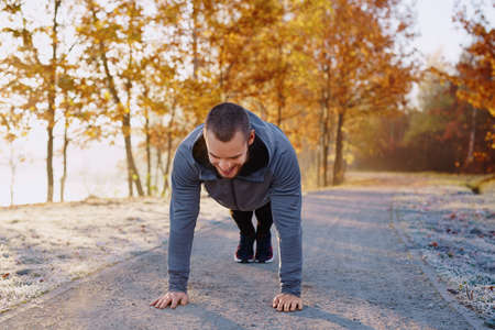 Happy man doing push ups exercise during morning running workoutの写真素材
