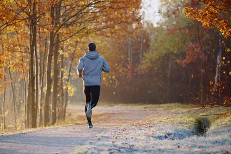 Young man running at park during autumn morningの写真素材