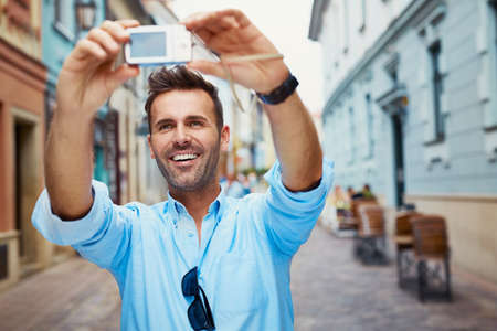 Handsome young man taking selfie with camera  on vacationの写真素材