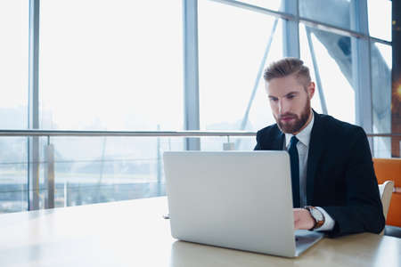 Successful businessman typing on laptop at modern office