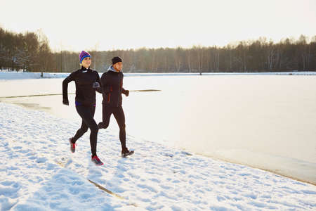Young couple running during winterの写真素材