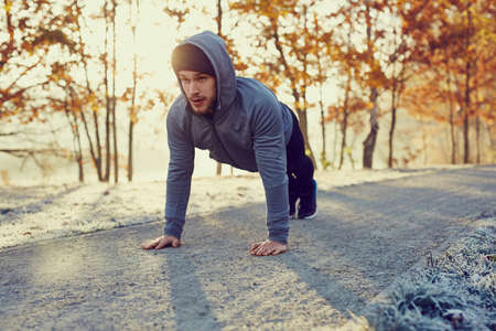 Young runner doing push ups exercise during cold autumn morningの写真素材