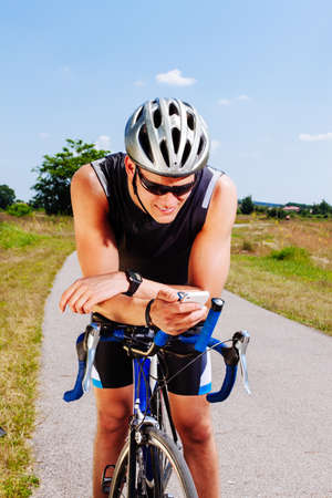 Triathlon cyclist texting on a smartphoneの写真素材