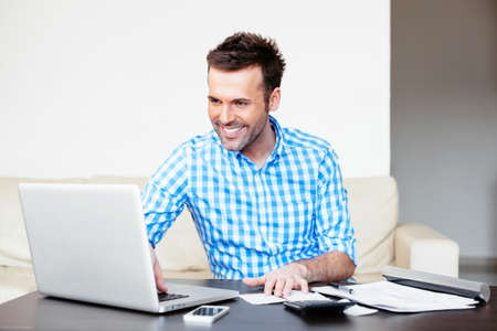 Handsome young man paying online using a laptopの写真素材
