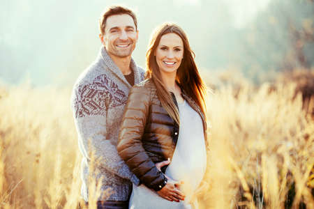 Happy young pregnant couple in natureの写真素材