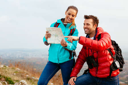 Happy couple reading map during autumn hiking.の写真素材