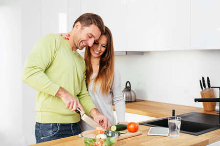 Happy pregnant couple preparing some food togetherの写真素材