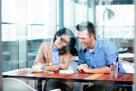 Smiling couple sitting at a table and taking notesの写真素材