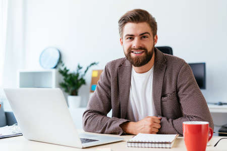 Concentrated businessman looking at laptop and analyzing. Portrait of young startup entrepreneur at workの写真素材